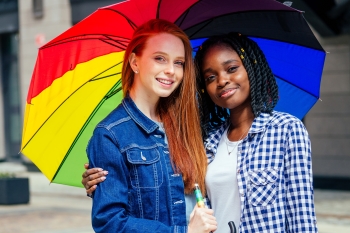 Two young people under a rainbow umbrella. image