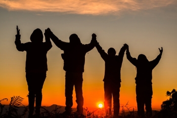 Teens holding hands and watching a sunset image