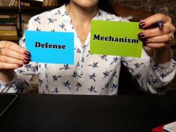 Person holding a sign that says defense mechanism image